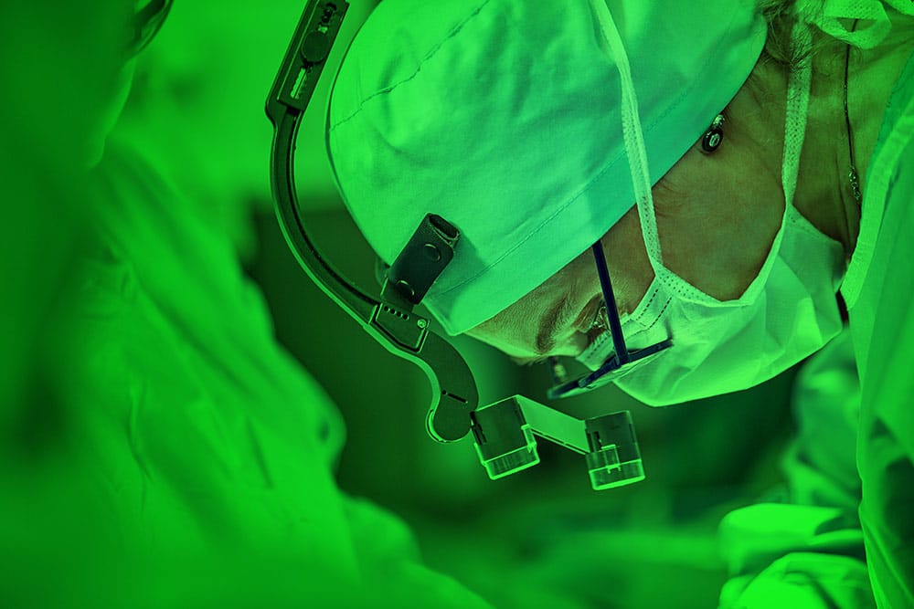 A surgeon working in green lighting to prevent eye strain